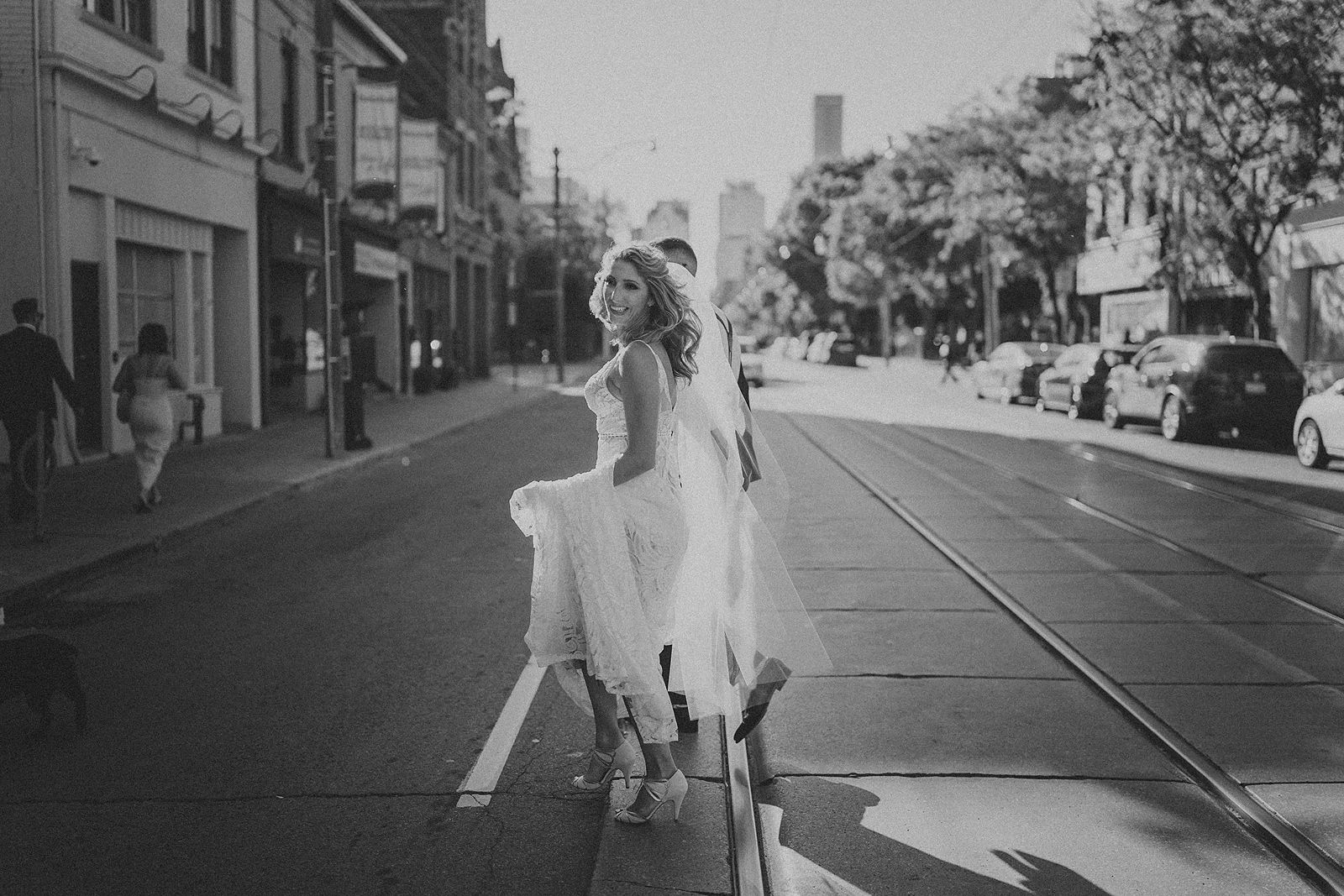 a bride looking back at the camera as she crosses the street in downtown Toronto