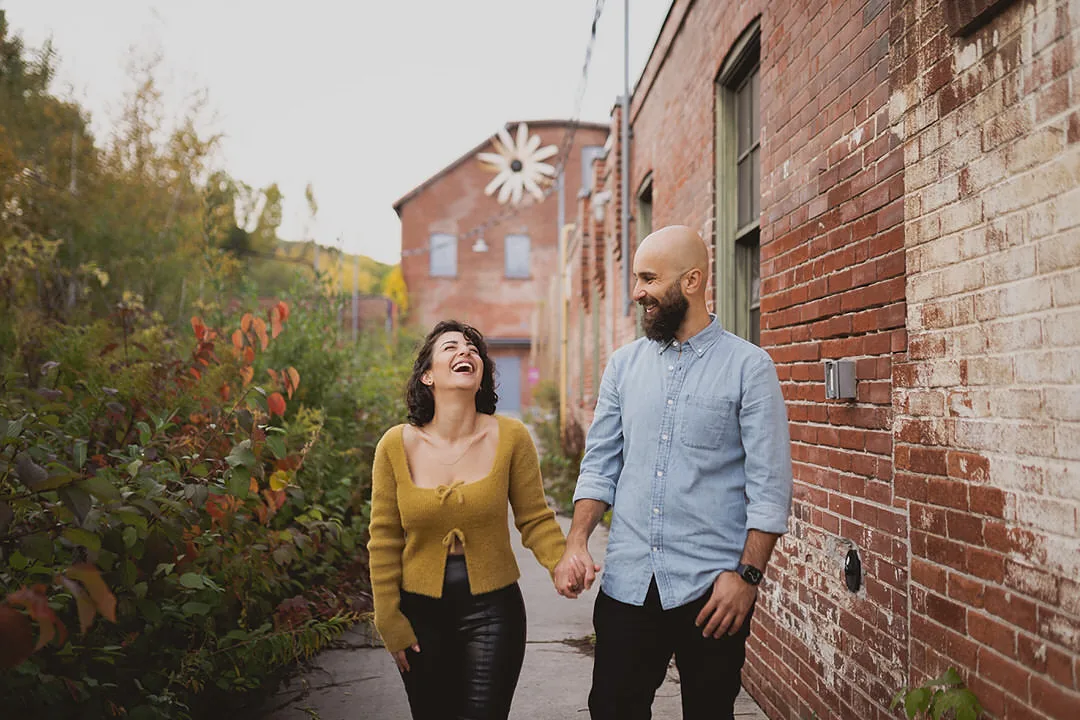 a couple walking together during their engagement photo session at the Toronto Brickworks