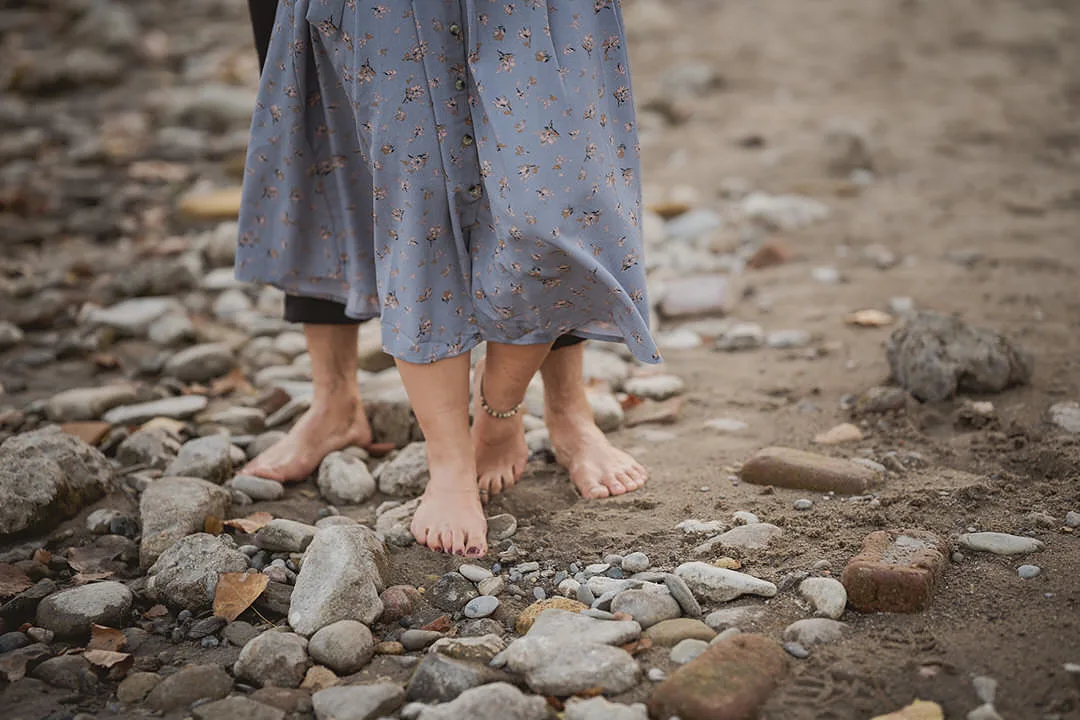 an engaged couple's bare feet on the beech