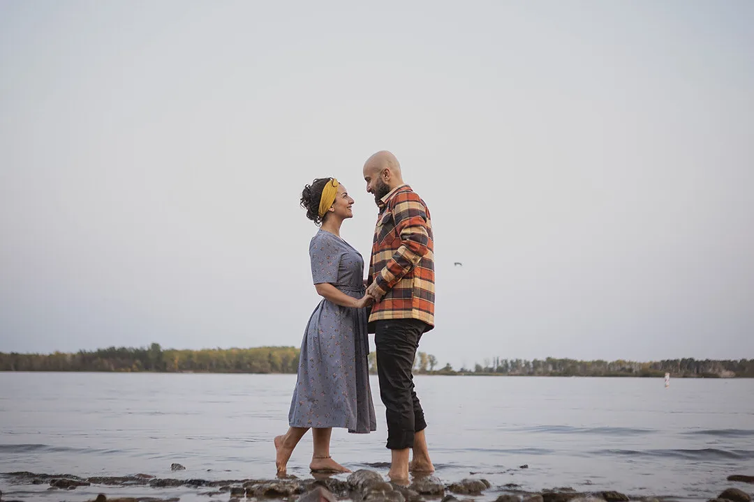 couple faces each other on the beech in Toronto during their engagement session