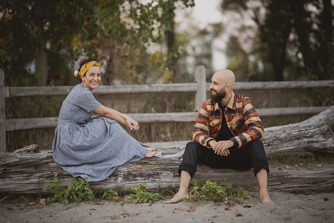 Couple sitting on a log on the beech in Toronto for their engagement photos