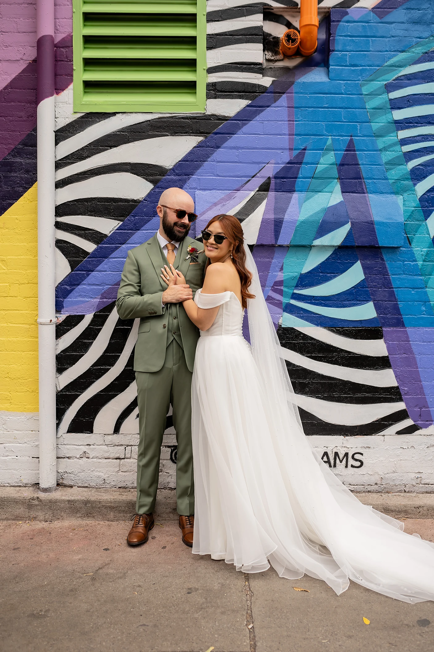 Bride and groom in front of graffiti wall with sunglasses