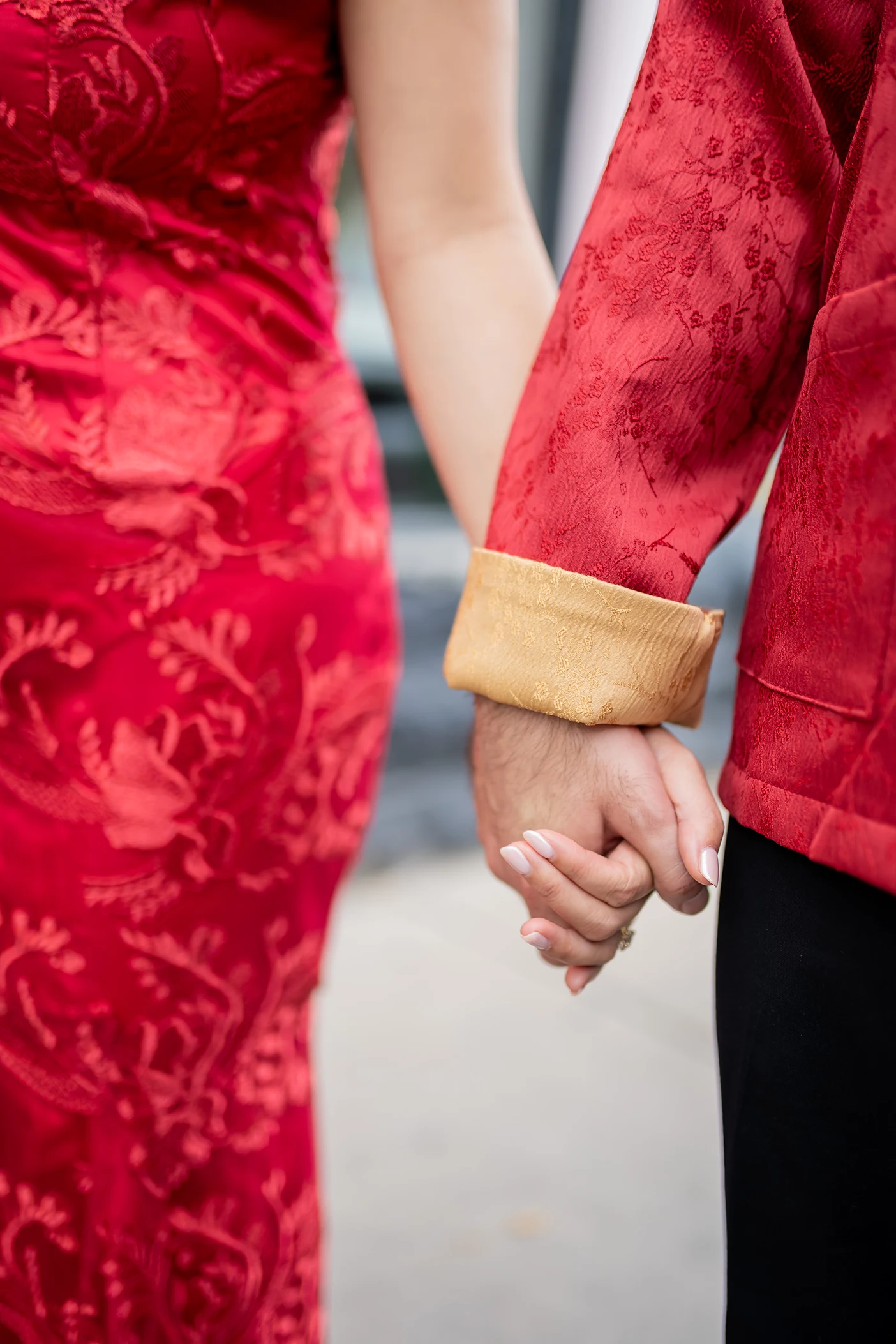 Bride and Groom hold hands wearing traditional Chinese wedding outfits