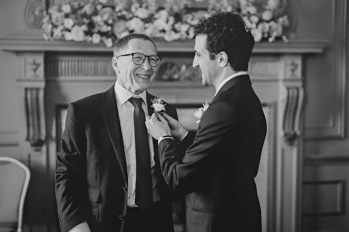 Mike pins a boutonniere on the bride's father