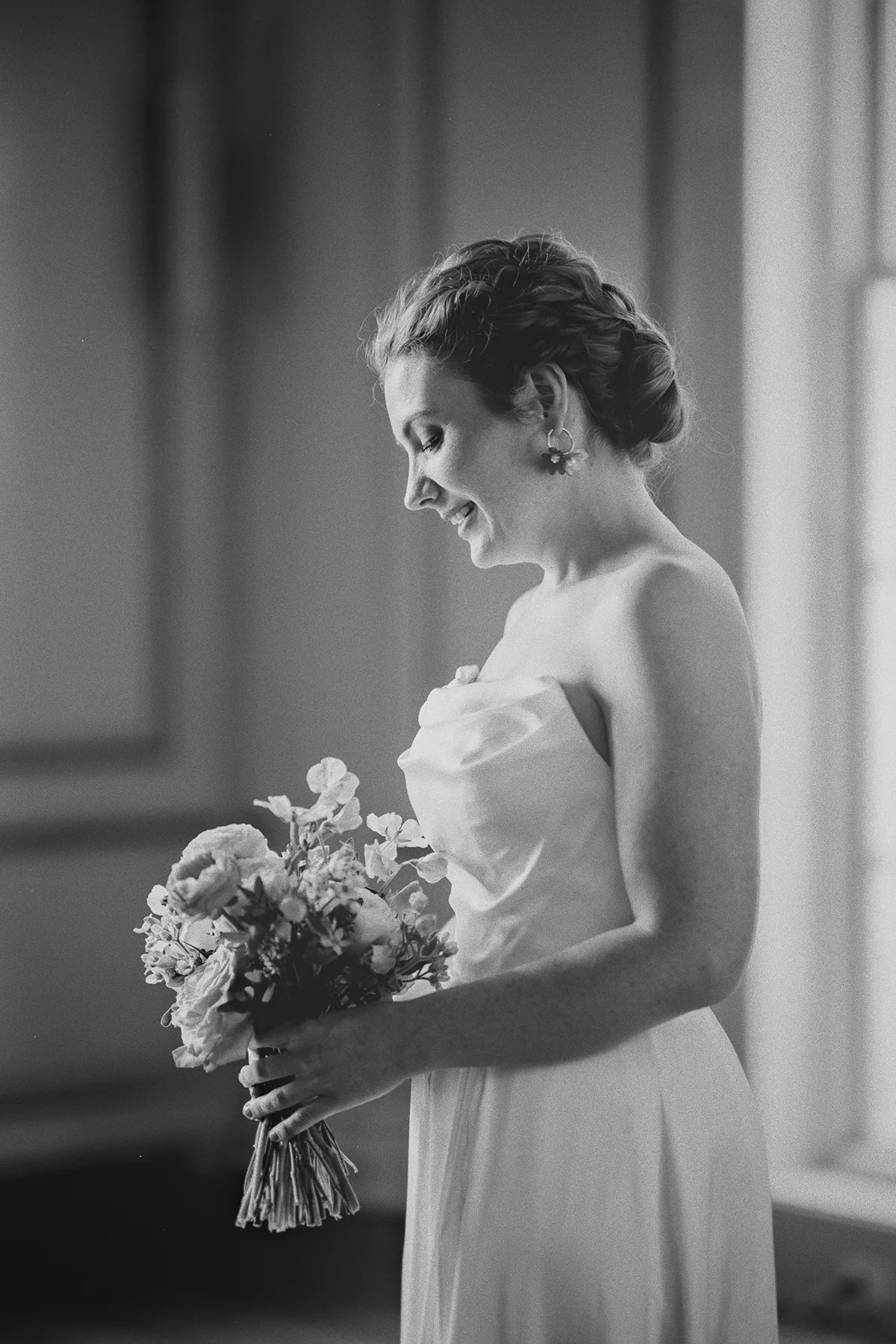A joyful candid of the bride looking at her bouquet