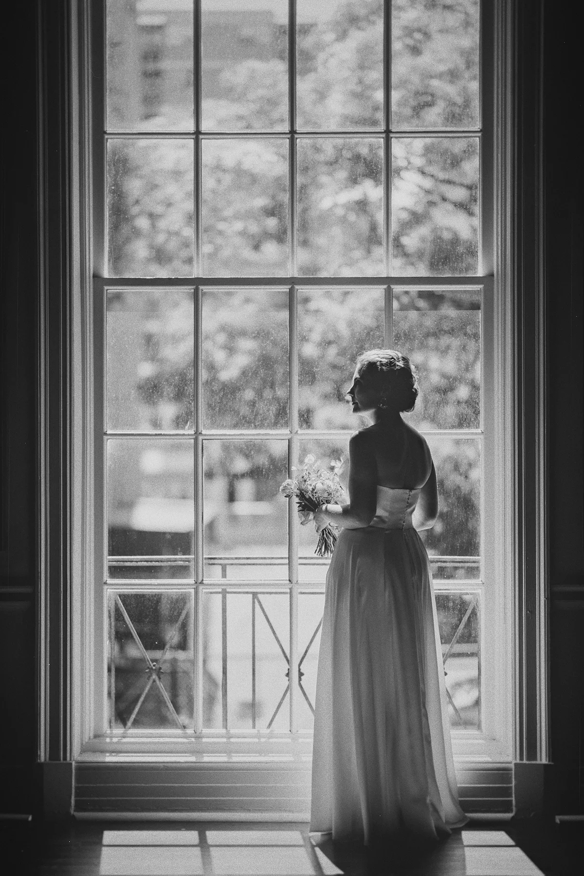 A dramatic portrait of Beth looking out a large window