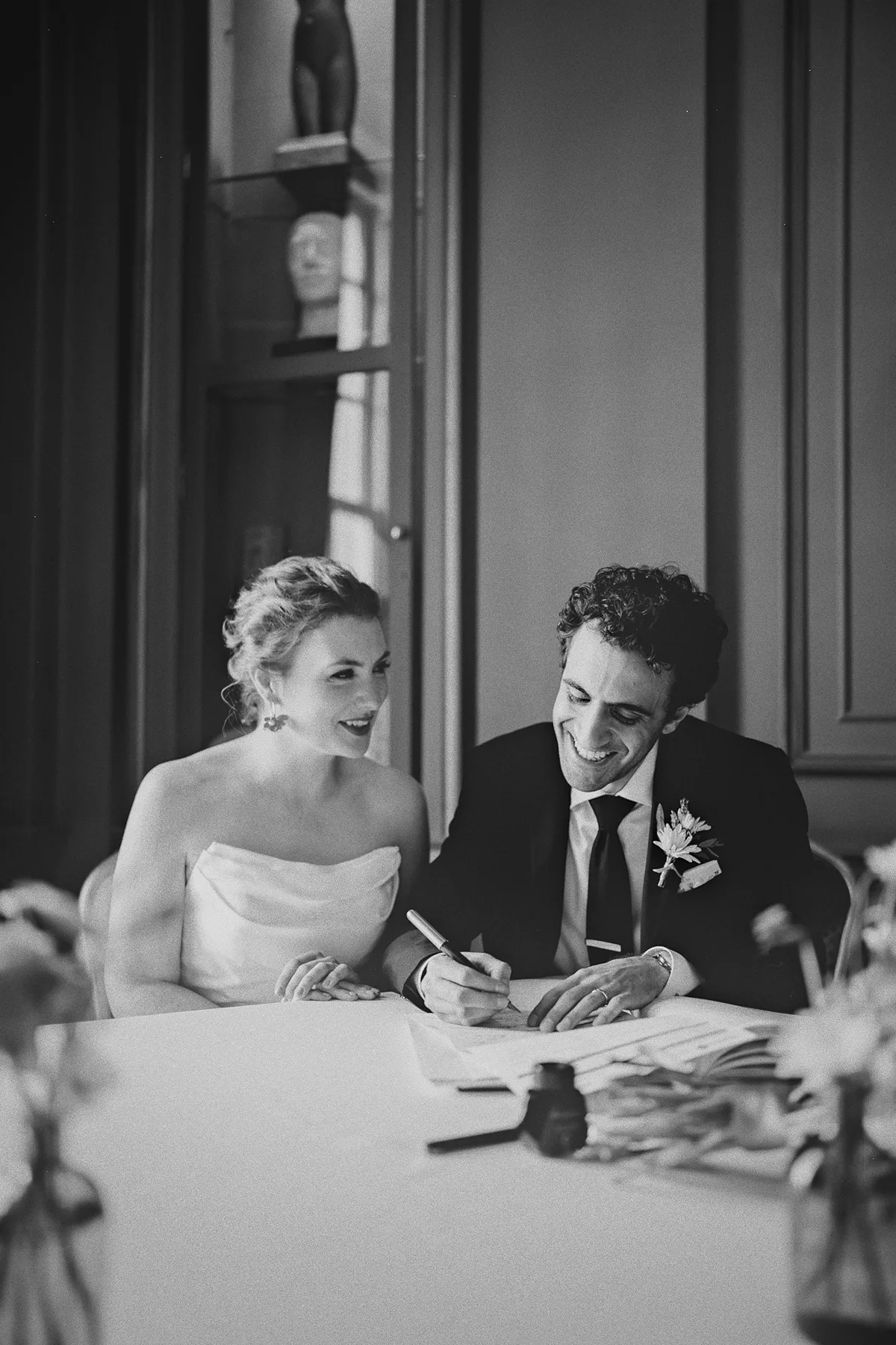 The couple smiles while signing their marriage license