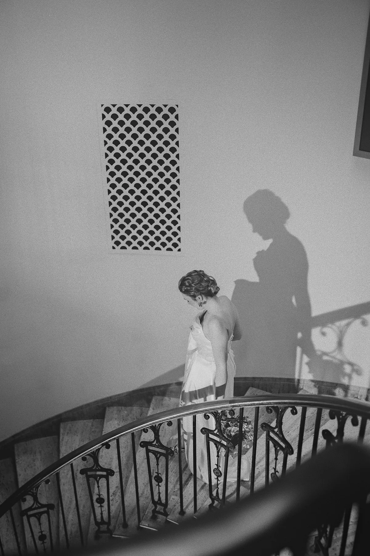 Beth walks down a spiral staircase in her wedding dress