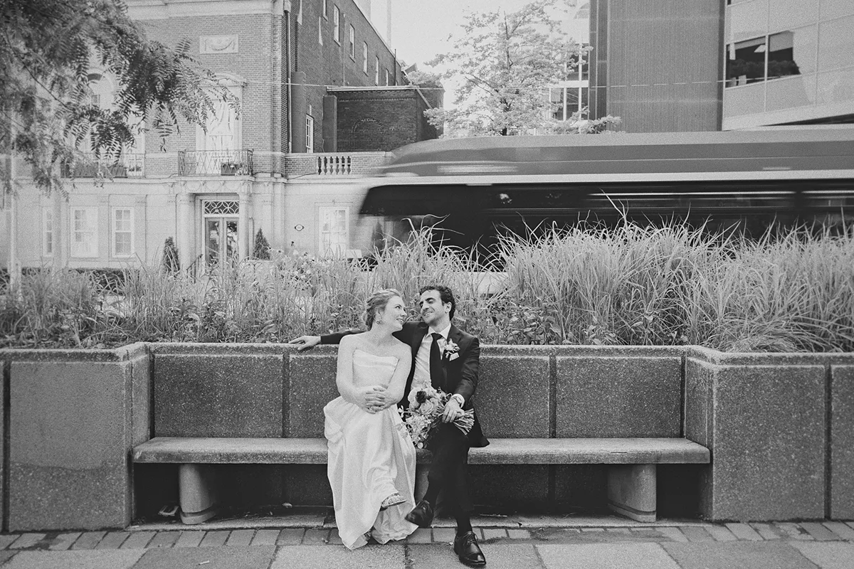 The couple sits on a bench as a streetcar blurs past