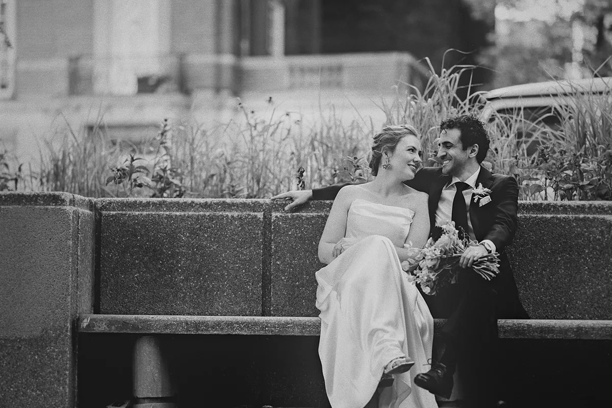 Mike looks at Beth as they sit on a bench