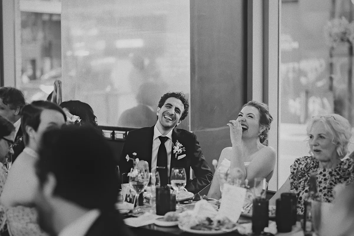 The couple throws their heads back laughing during a speech