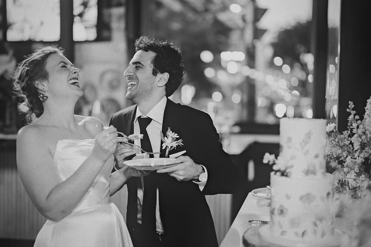 The couple laughs before feeding each other cake