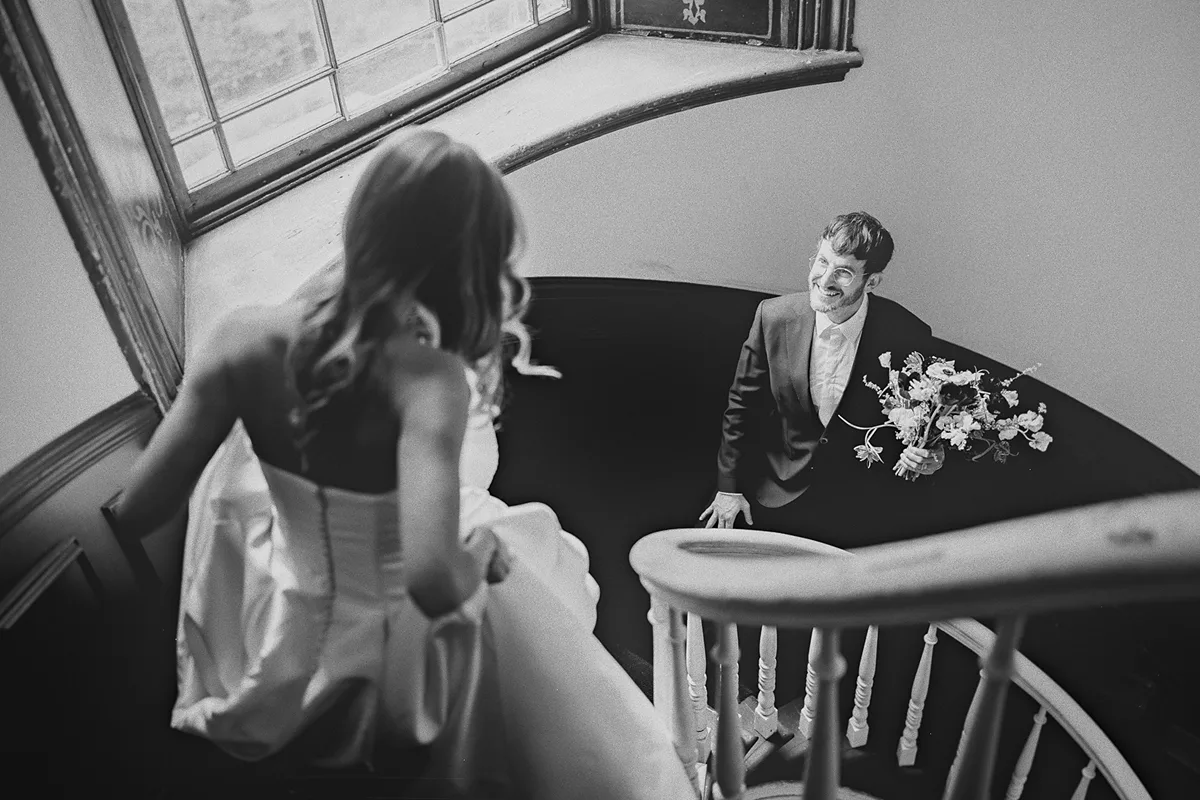 Mark looks up at Carolyn on a spiral staircase