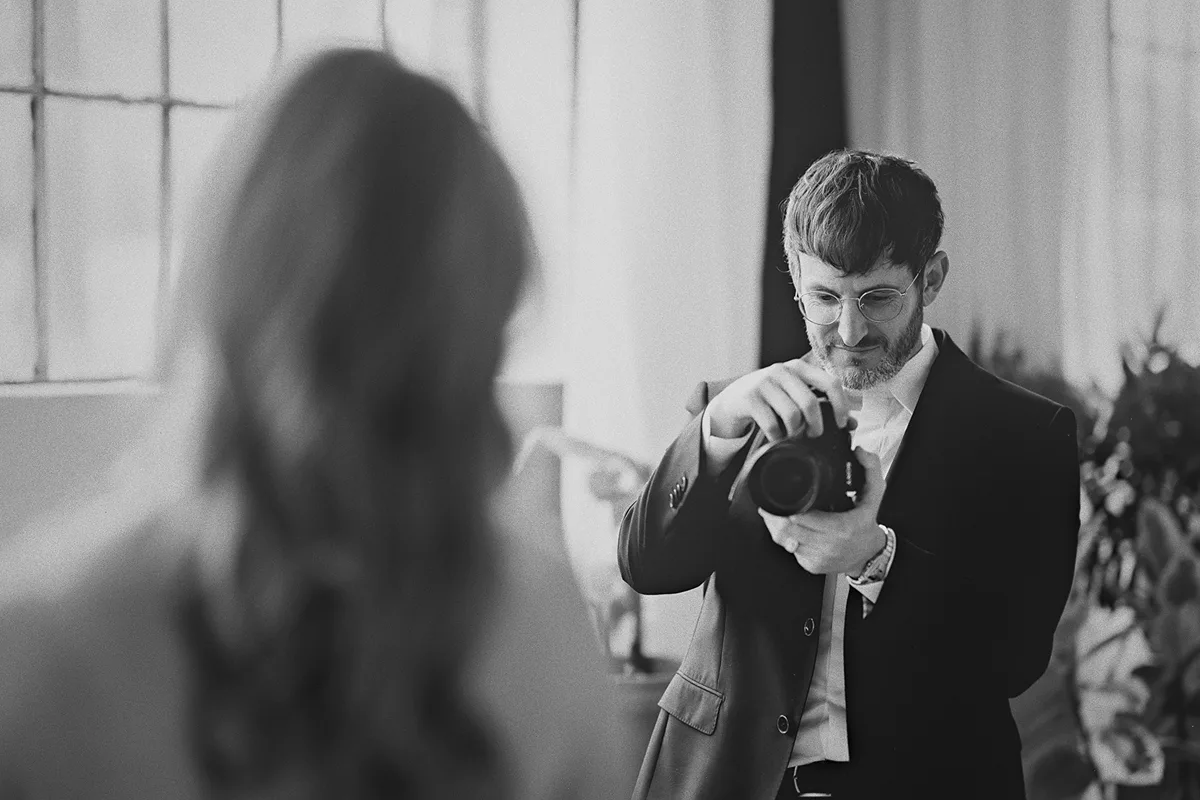 The groom, a filmmaker, photographs his bride