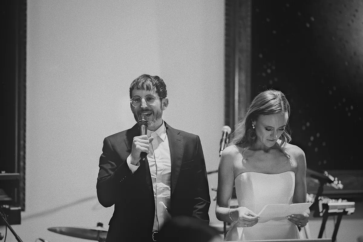 Mark gives a speech as Carolyn looks at her notes
