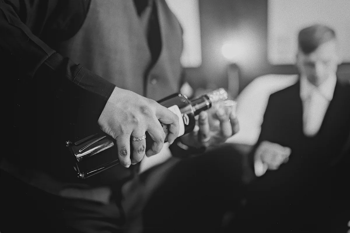A groomsman pours a pre-wedding drink