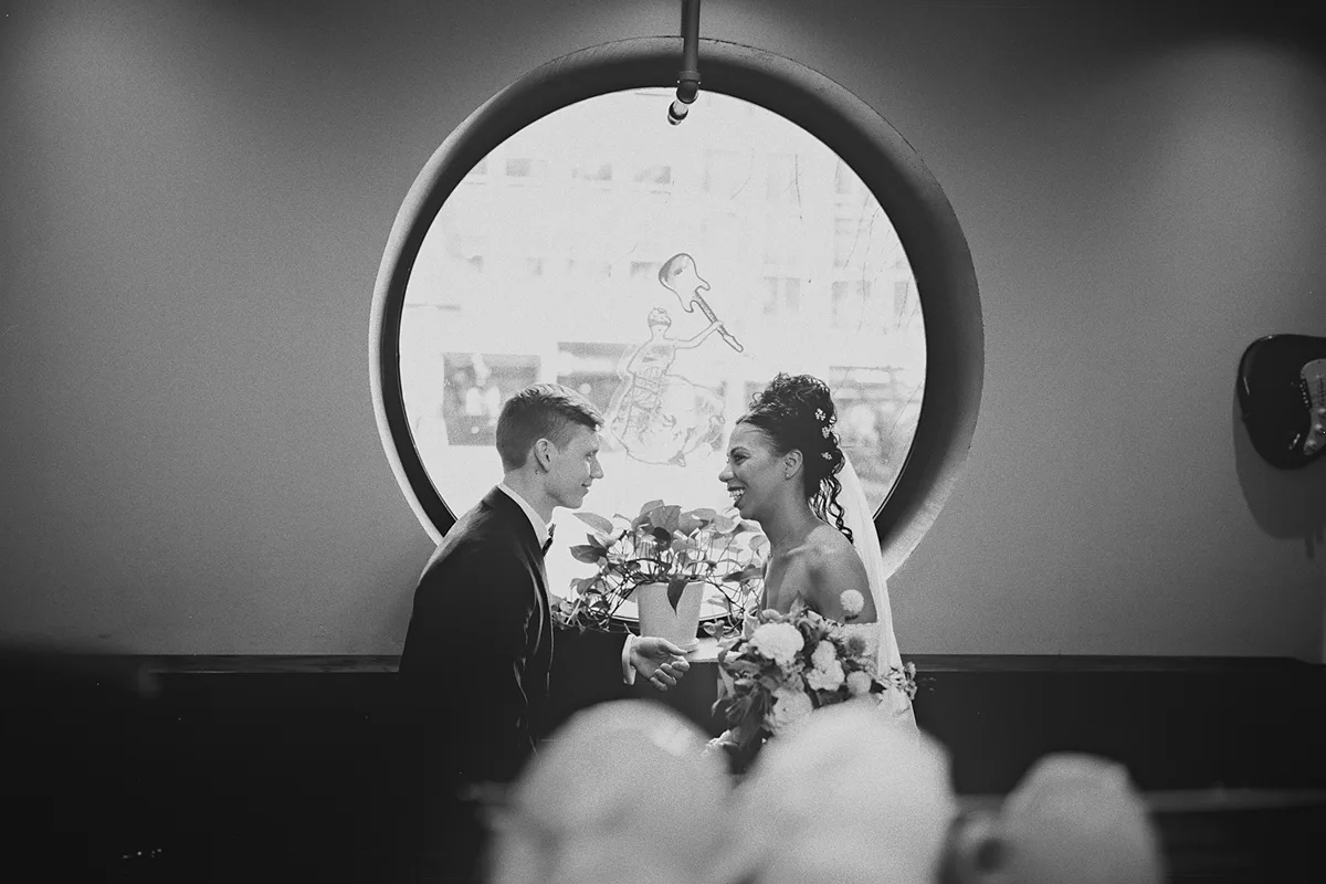Cherise and Konrad laugh together by a round window
