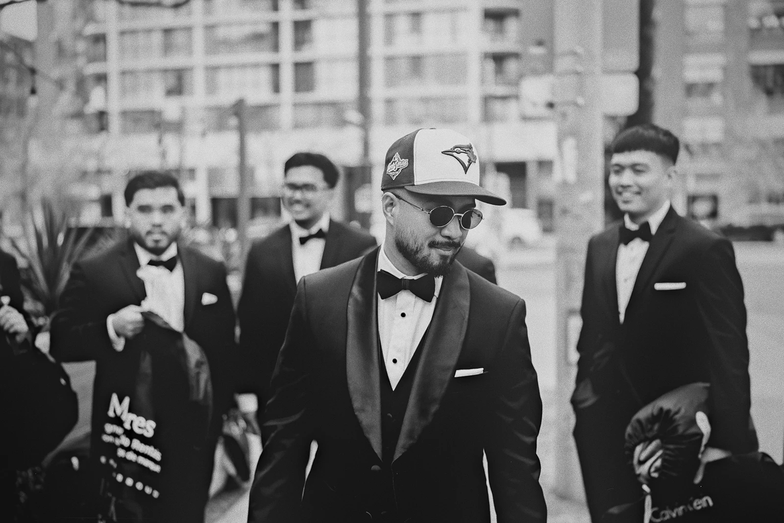 Jamie walks with his groomsmen wearing a Blue Jays hat