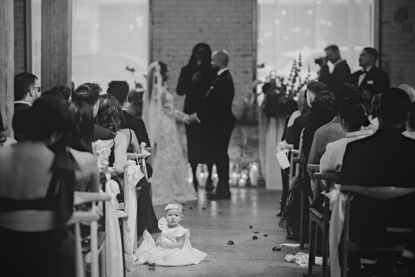 A baby sits in the aisle during the wedding ceremony