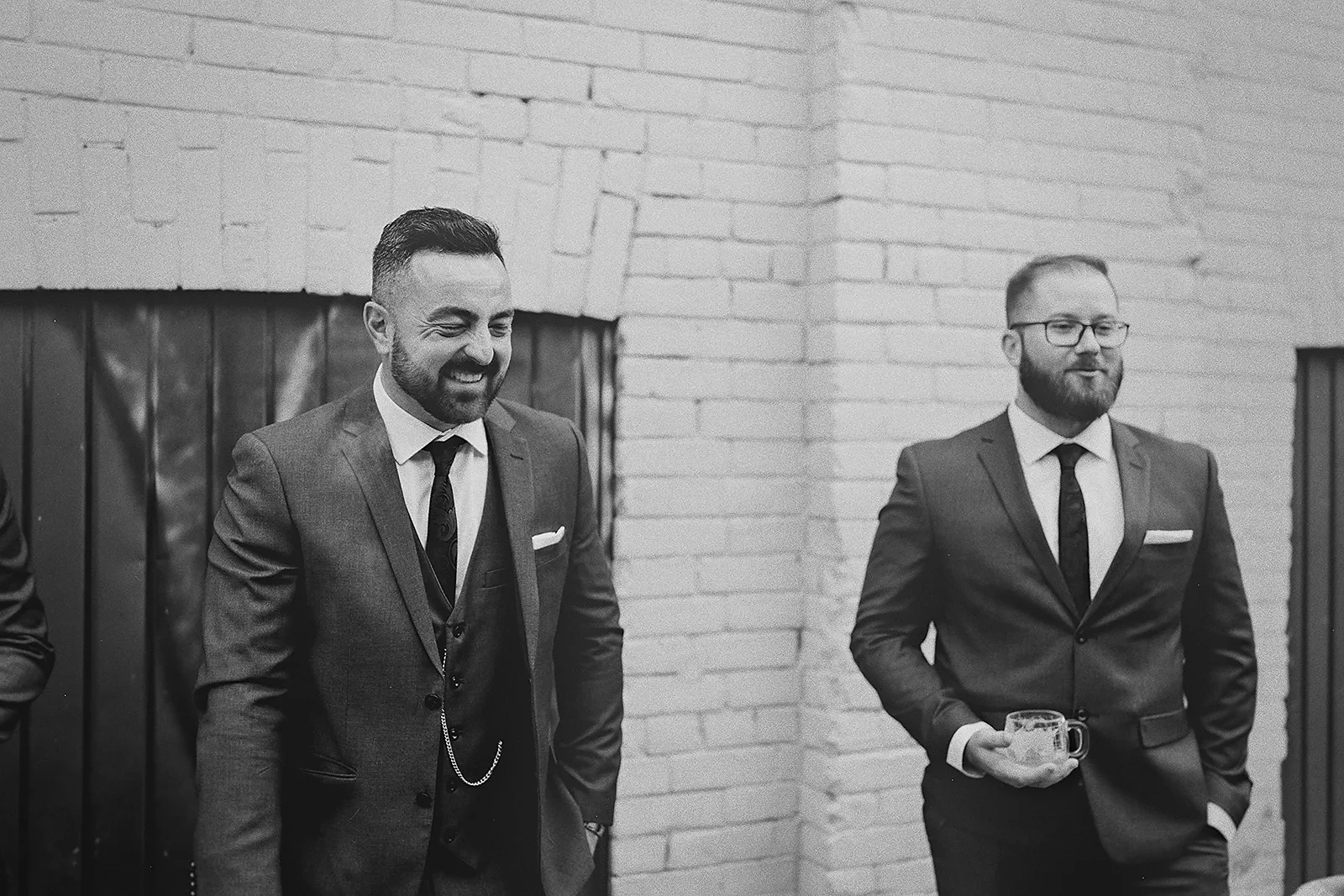 Two groomsmen smile during outdoor portraits