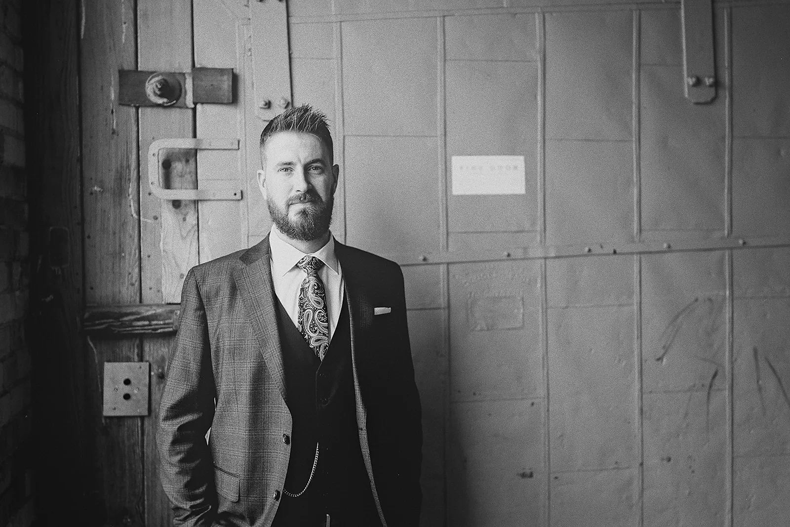 Ryan poses for a portrait against an industrial door