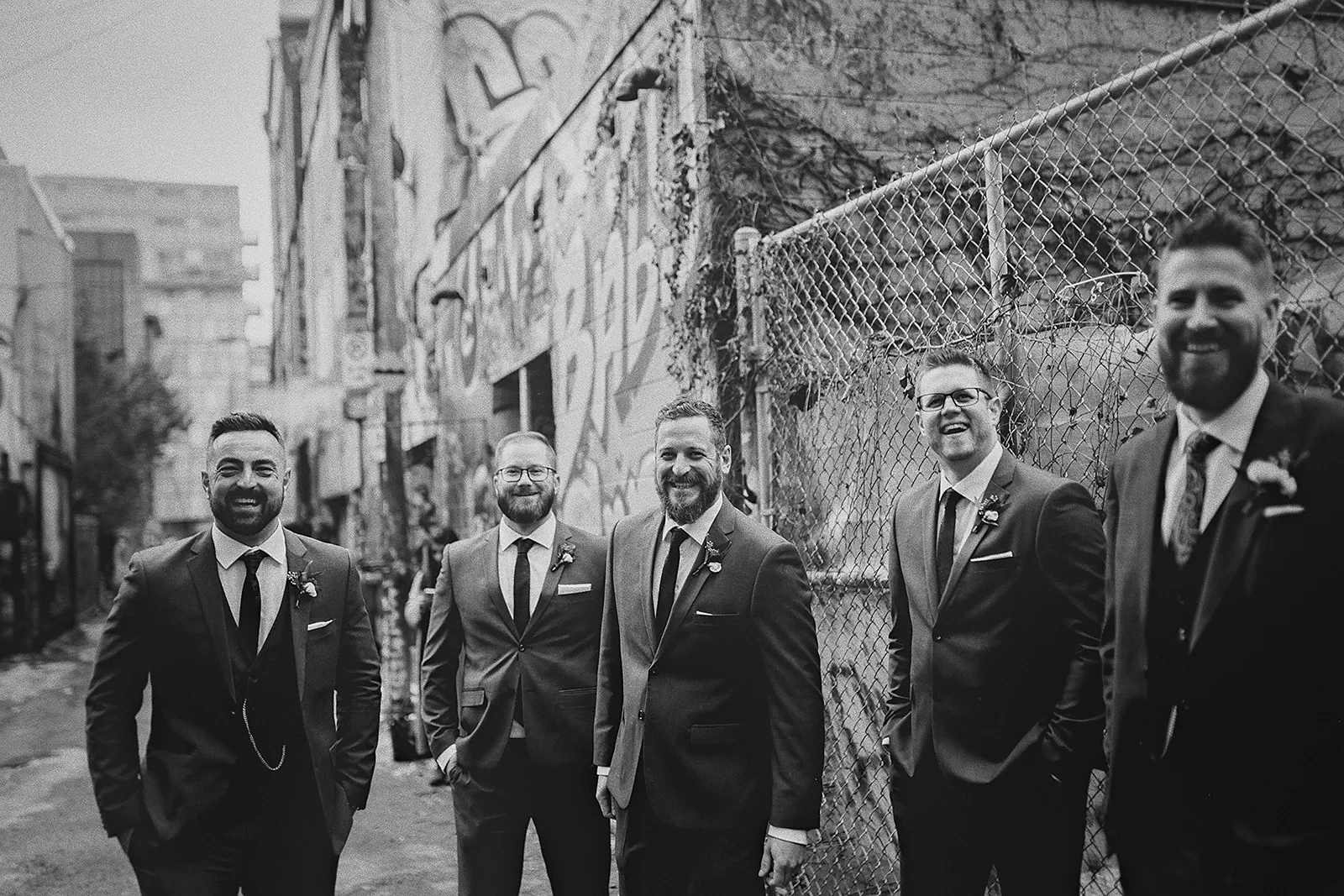 Ryan and his groomsmen laugh together in Graffiti Alley