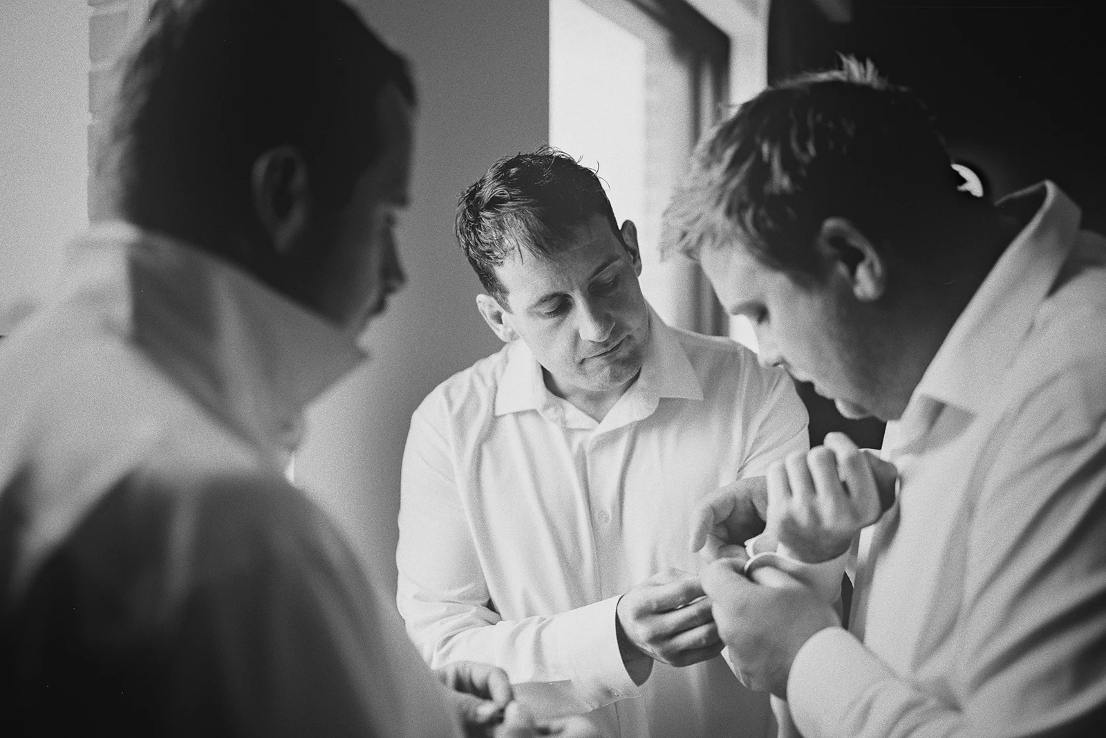 Groomsmen work together to put on cufflinks