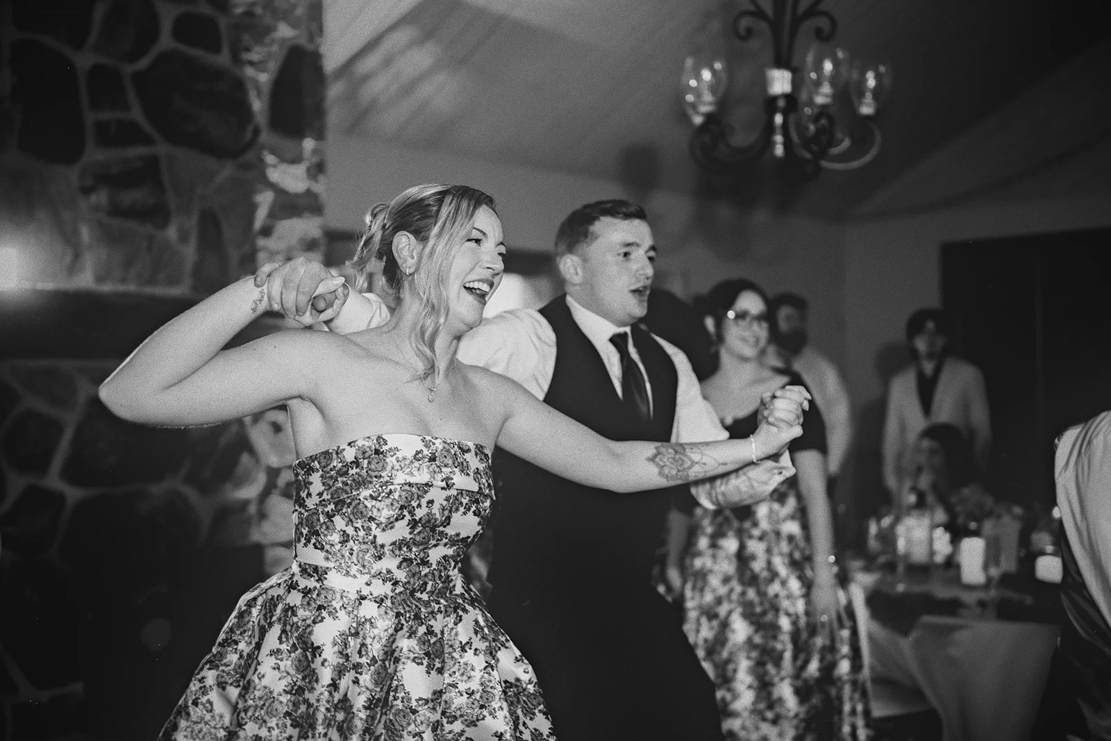A bridesmaid and groomsman dance with their arms up.
