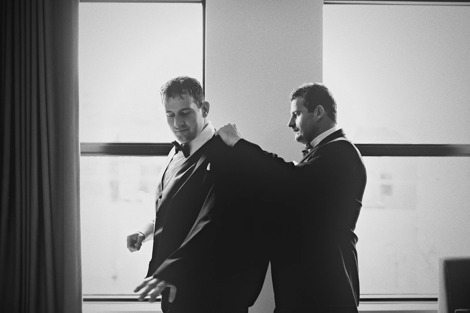 A silhouette of a groomsman helping the groom