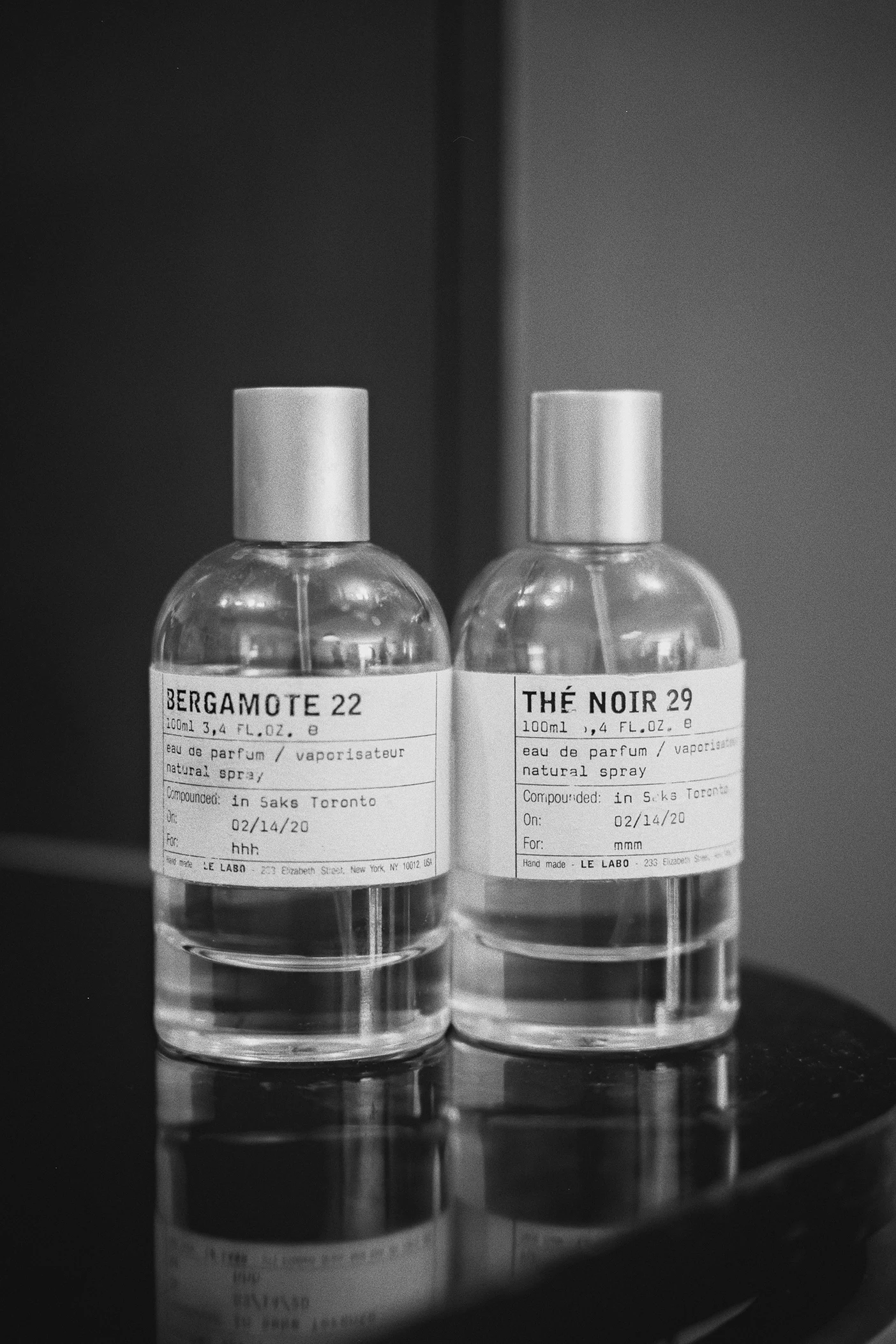 Two bottles of Le Labo cologne, Bergamote 22 and The Noir 29, sit on a reflective surface.