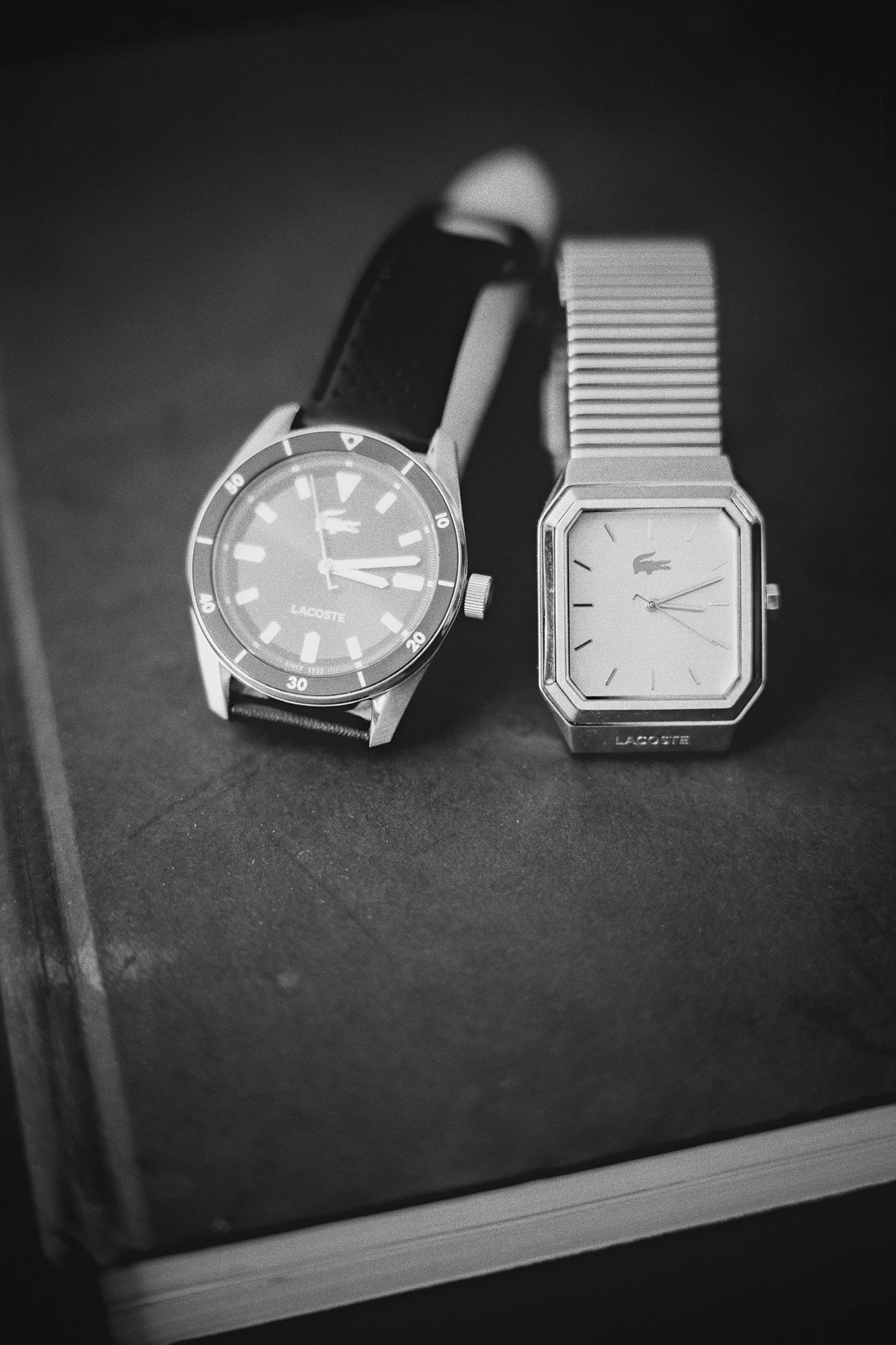 The grooms' watches, one with a green face and one with a silver band, rest on a book.