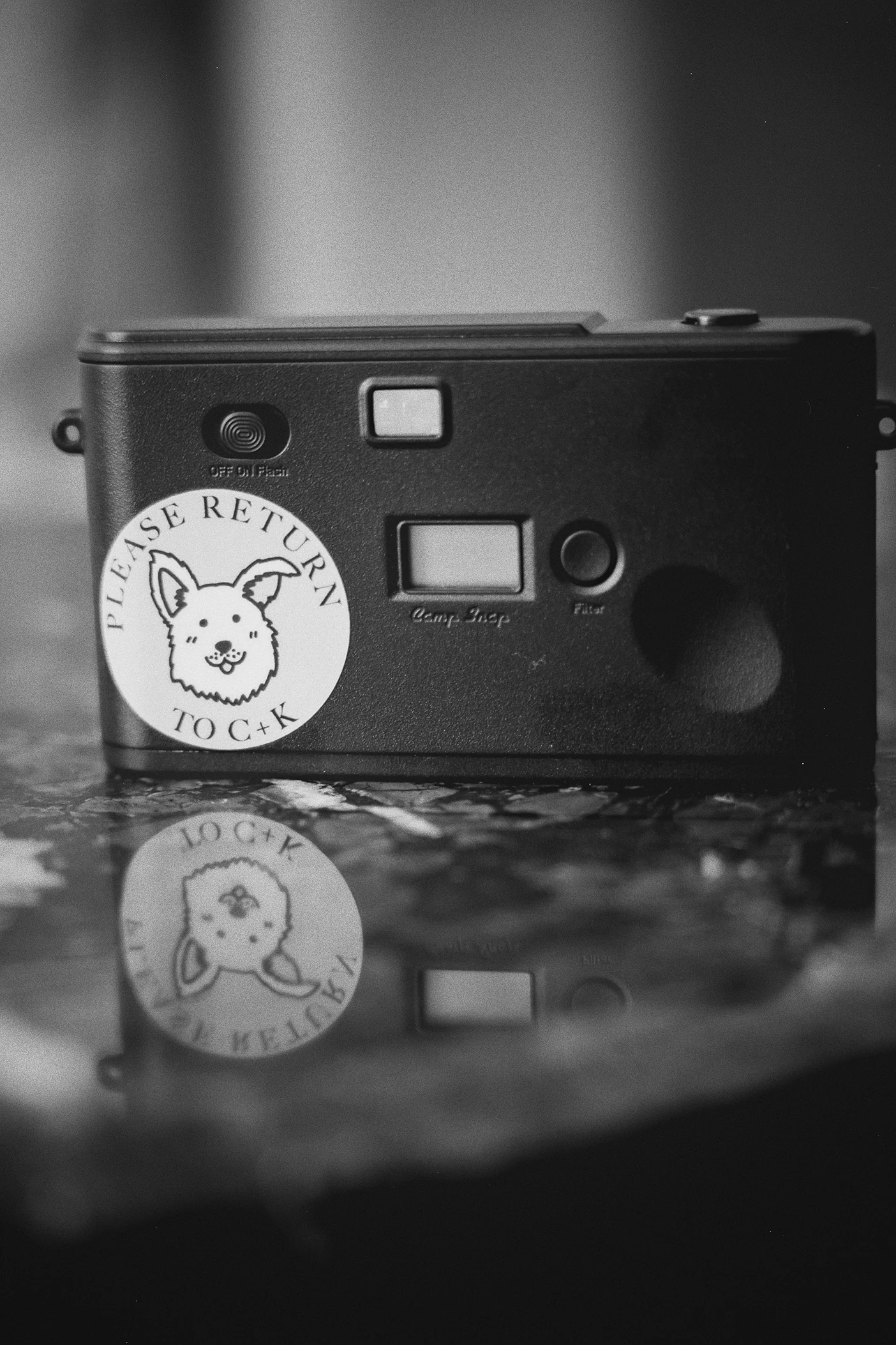 The back of a camera features a custom sticker of a dog and initials.