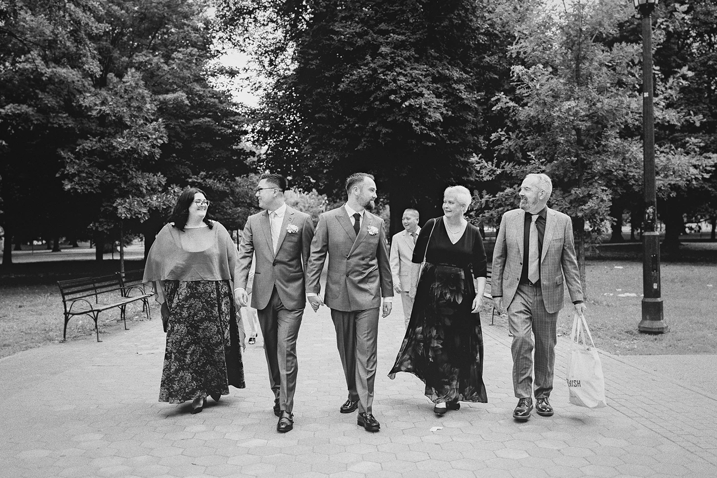 The couple walks hand-in-hand, leading their family through the park to the venue.