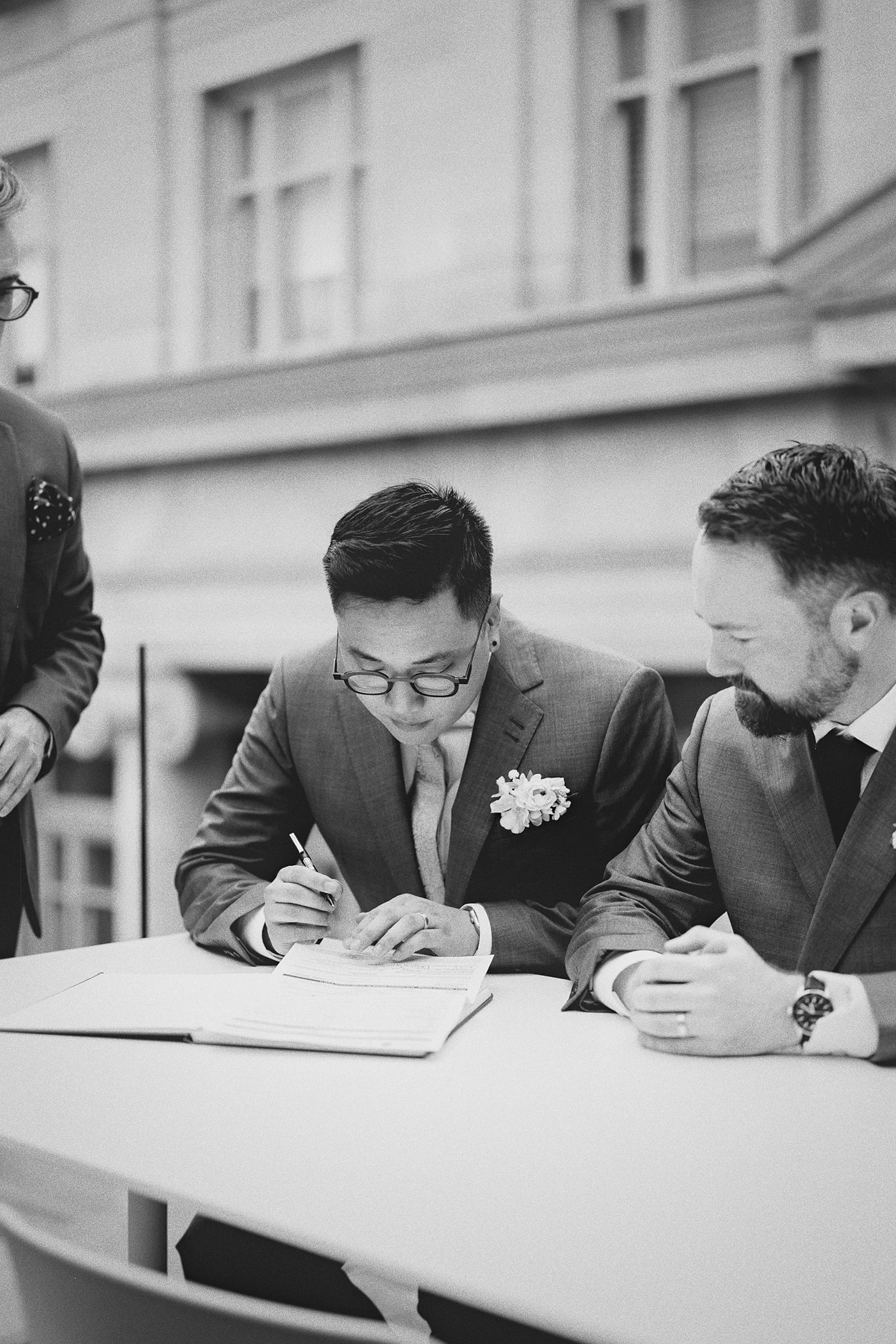 Ky carefully signs the marriage license as Connor watches over his shoulder.