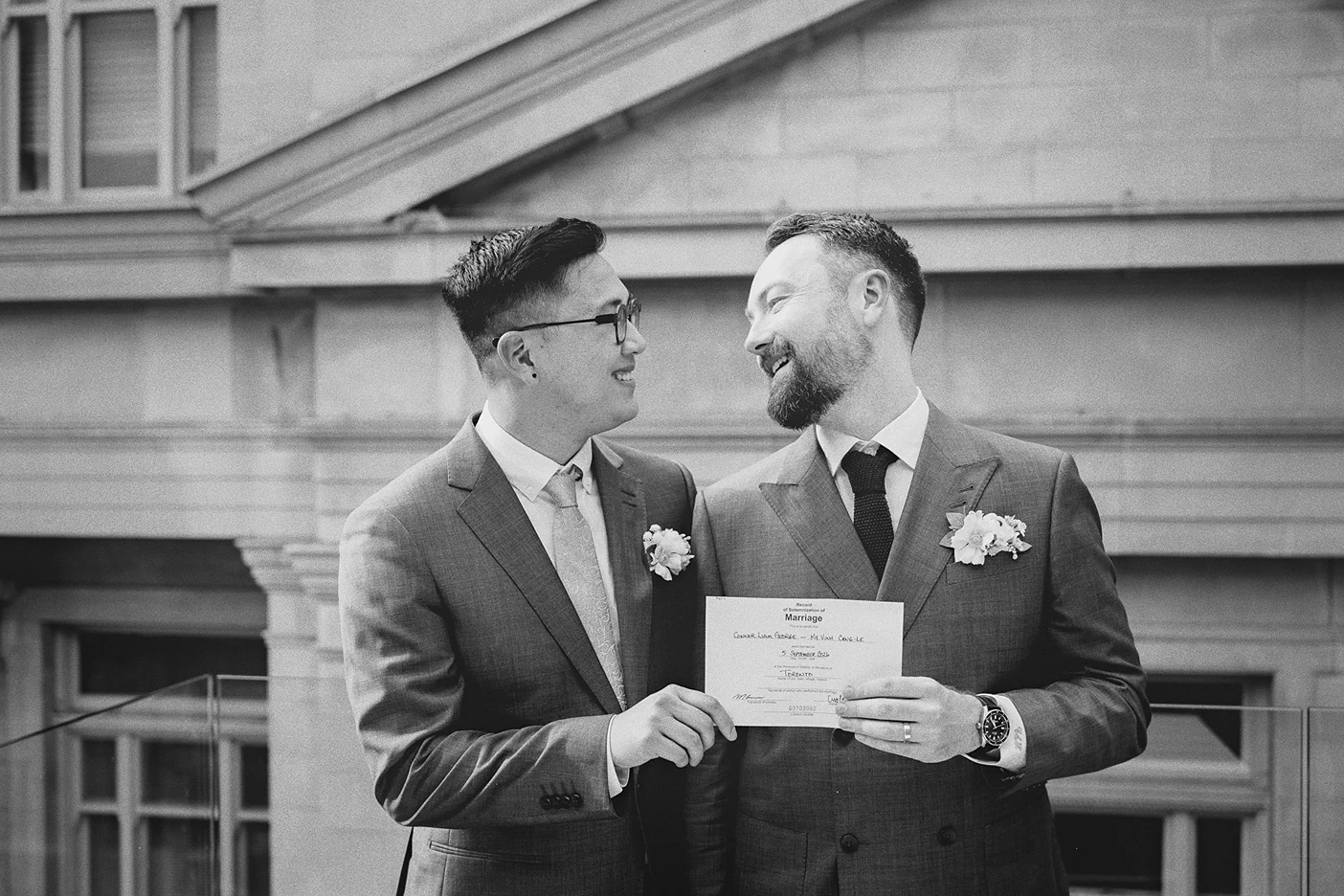 The grooms proudly hold up their official marriage certificate.