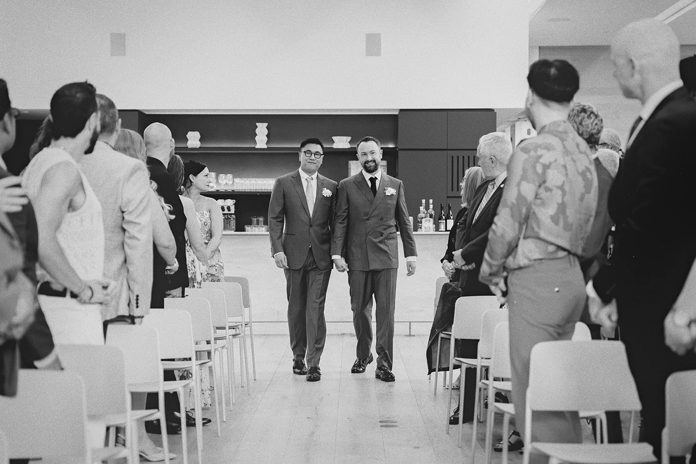 The grooms walk down the aisle together, hand in hand.