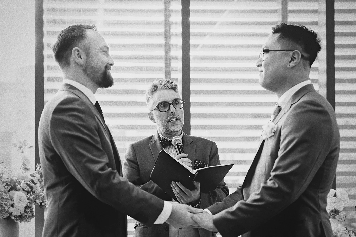 The couple holds hands and smiles at each other during their wedding ceremony.