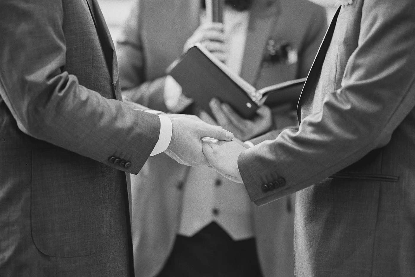 A close-up shows the couple holding hands during their vows.