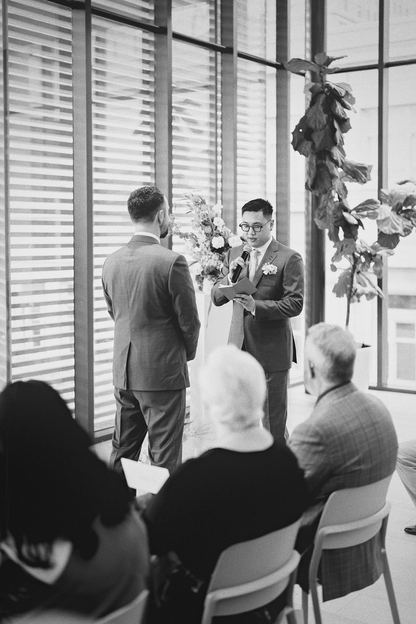 Ky reads his vows to Connor, with guests looking on.