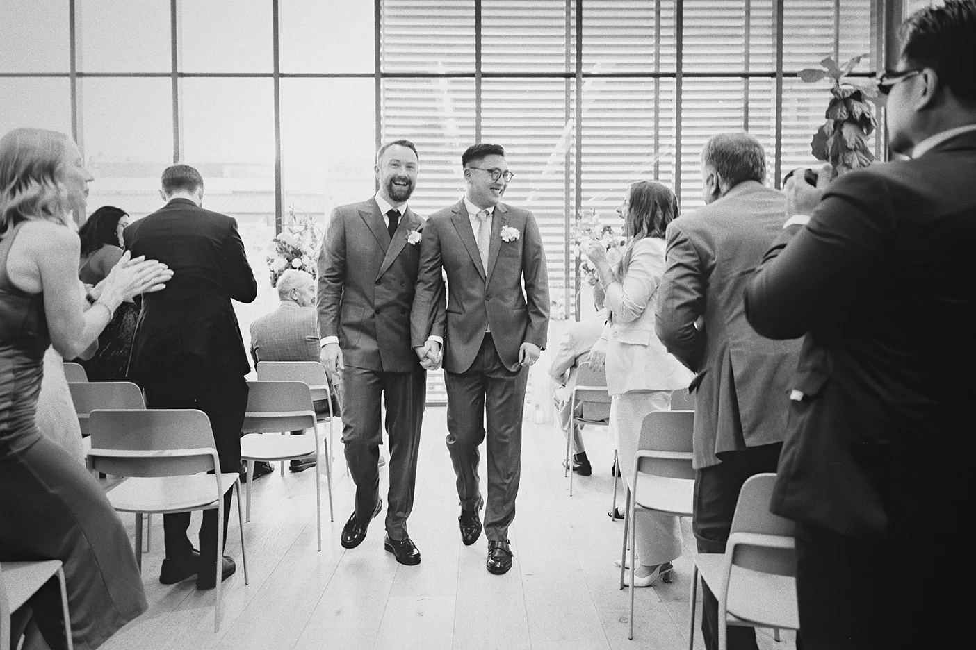 The newlyweds walk down the aisle, greeted by cheering guests.