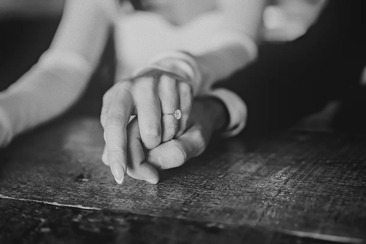 A close-up of the couple holding hands, showing Roxy's ring.