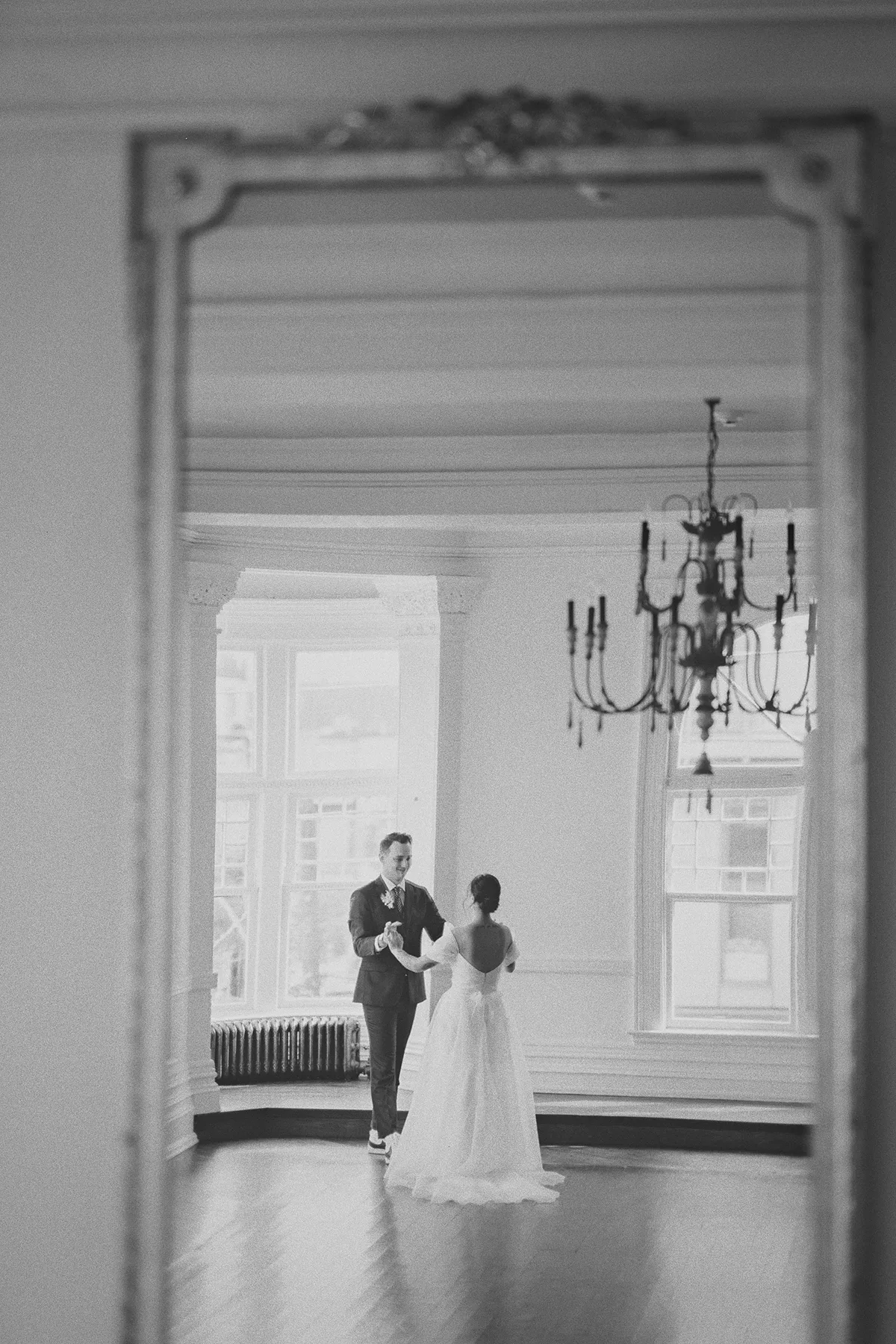 The couple's first look captured in a soft-focus mirror reflection.