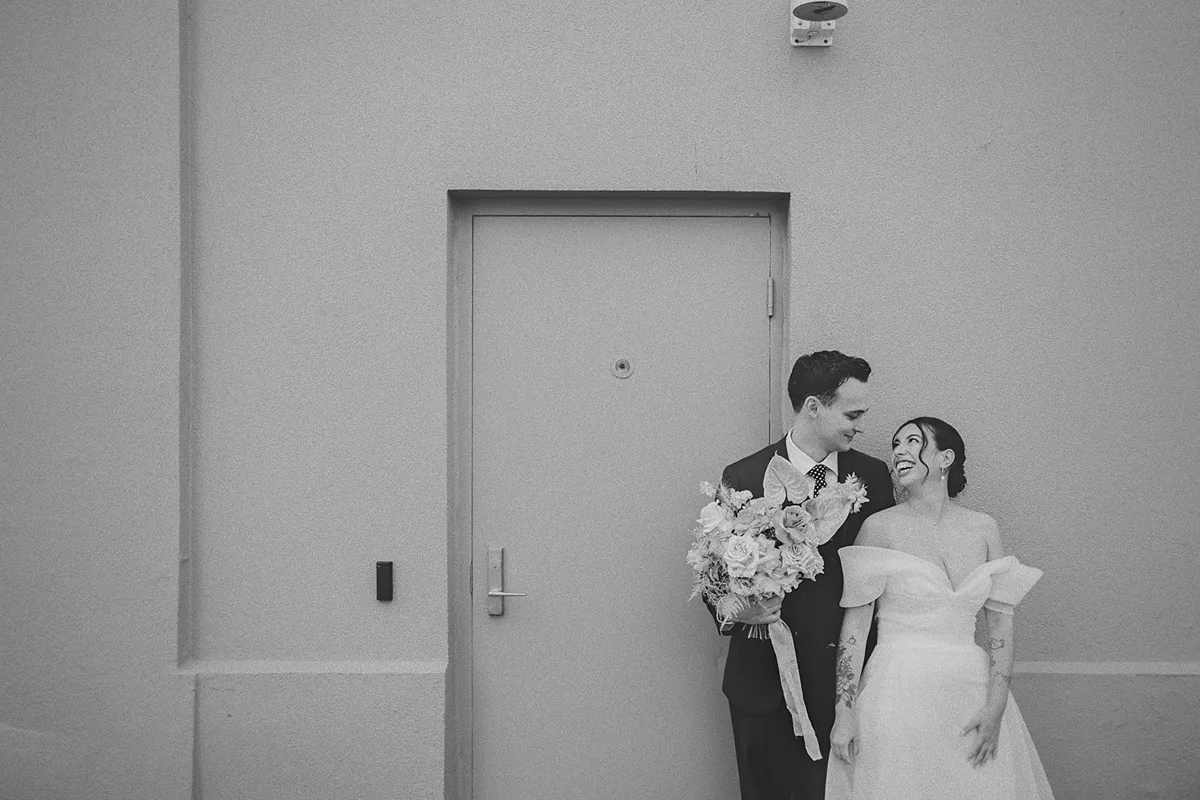 A romantic portrait of the couple against a green wall.