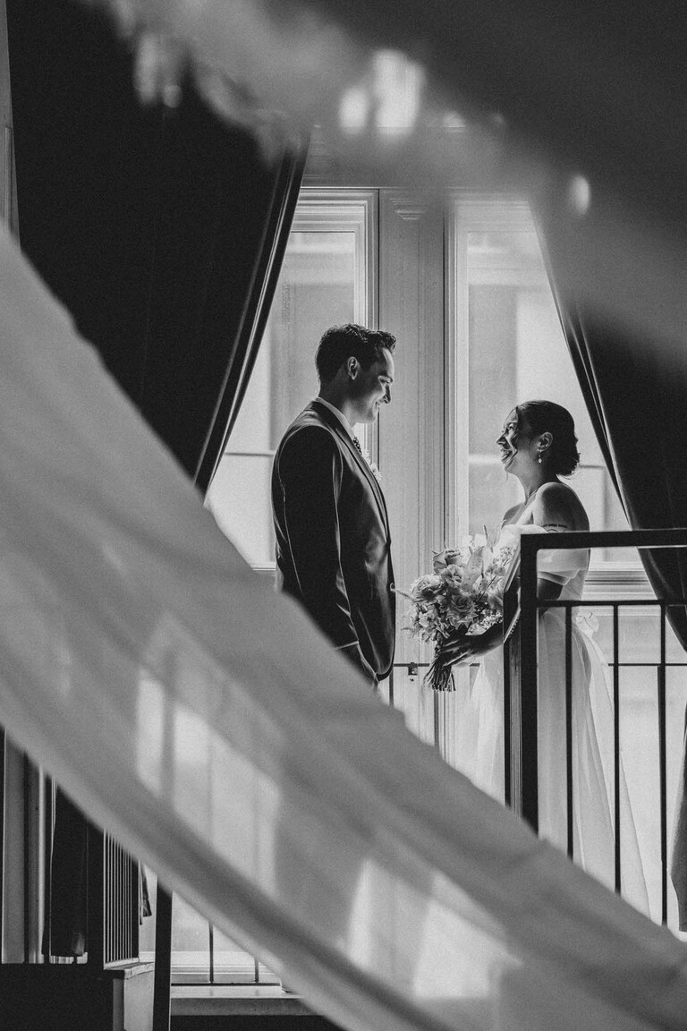 Bride and Groom smile at each other in front of a tall window inside The Great Hall for their Wedding
