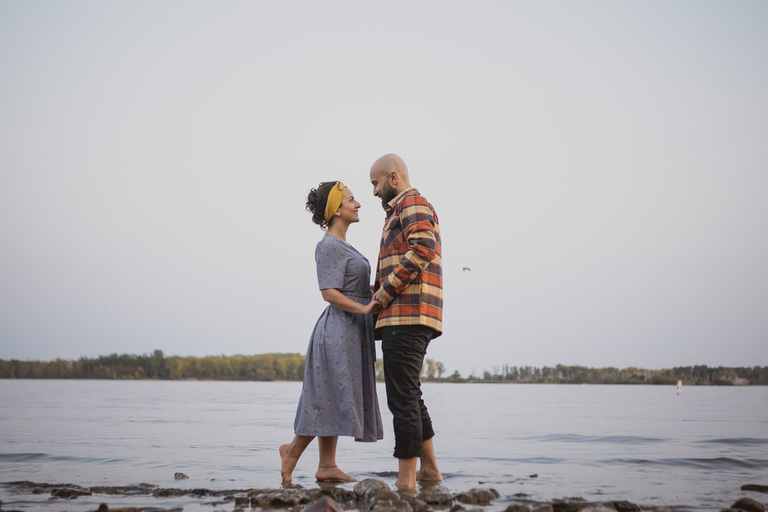couple faces each other on the beech in Toronto during their engagement session