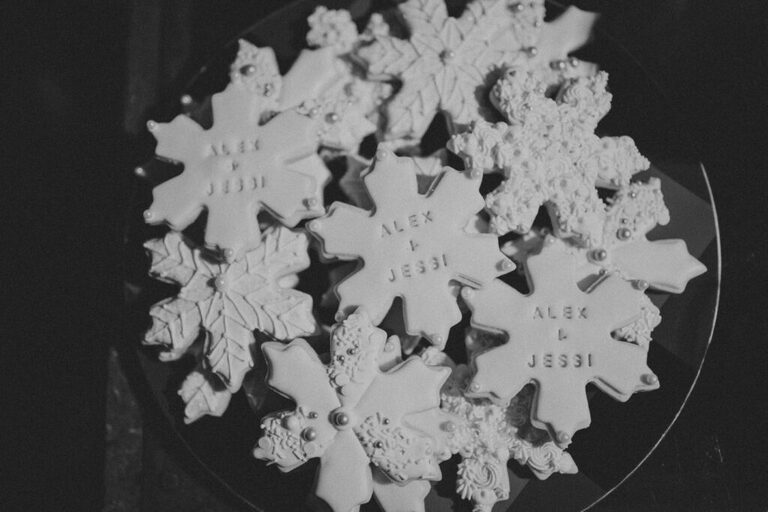 A plate of snowflake sugar cookies that are decorated with the bride and groom's first names.