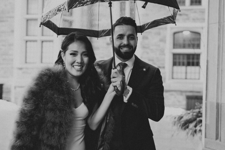 Bride and Groom standing together smiling at the camera.  They came to their Toronto winter wedding photo shoot prepared with an umbrella and fur wrap to keep warm.
